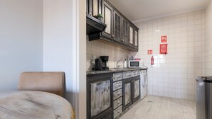 A kitchen with dark wooden cabinets, a microwave, a coffee maker, and a trash bin. - MyRiverPlace N.5 - PORTO Riverfront Apartment With Breathtaking Views (Vila Nova de Gaia)