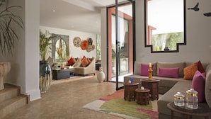 A spacious living area with a large window, a sofa set, a coffee table, and decorative wall art.