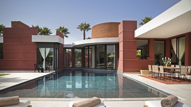 A modern pool area with lounge chairs, a dining table, and a clear view of the pool.