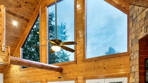 A spacious living room with a large wooden ceiling, a fireplace, and a stone wall. There is a sofa set and a coffee table in the center. - Insta-Worthy⛰Views 😍 ***Seasonal Discount*** ❤️️ Fire Pit. Hot Tub & Arcade (Sevierville)