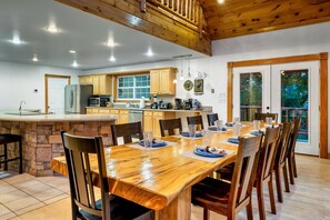 Une cuisine spacieuse dotée de meubles en bois, d’un îlot central et d’un coin repas avec une grande table et des chaises en bois.