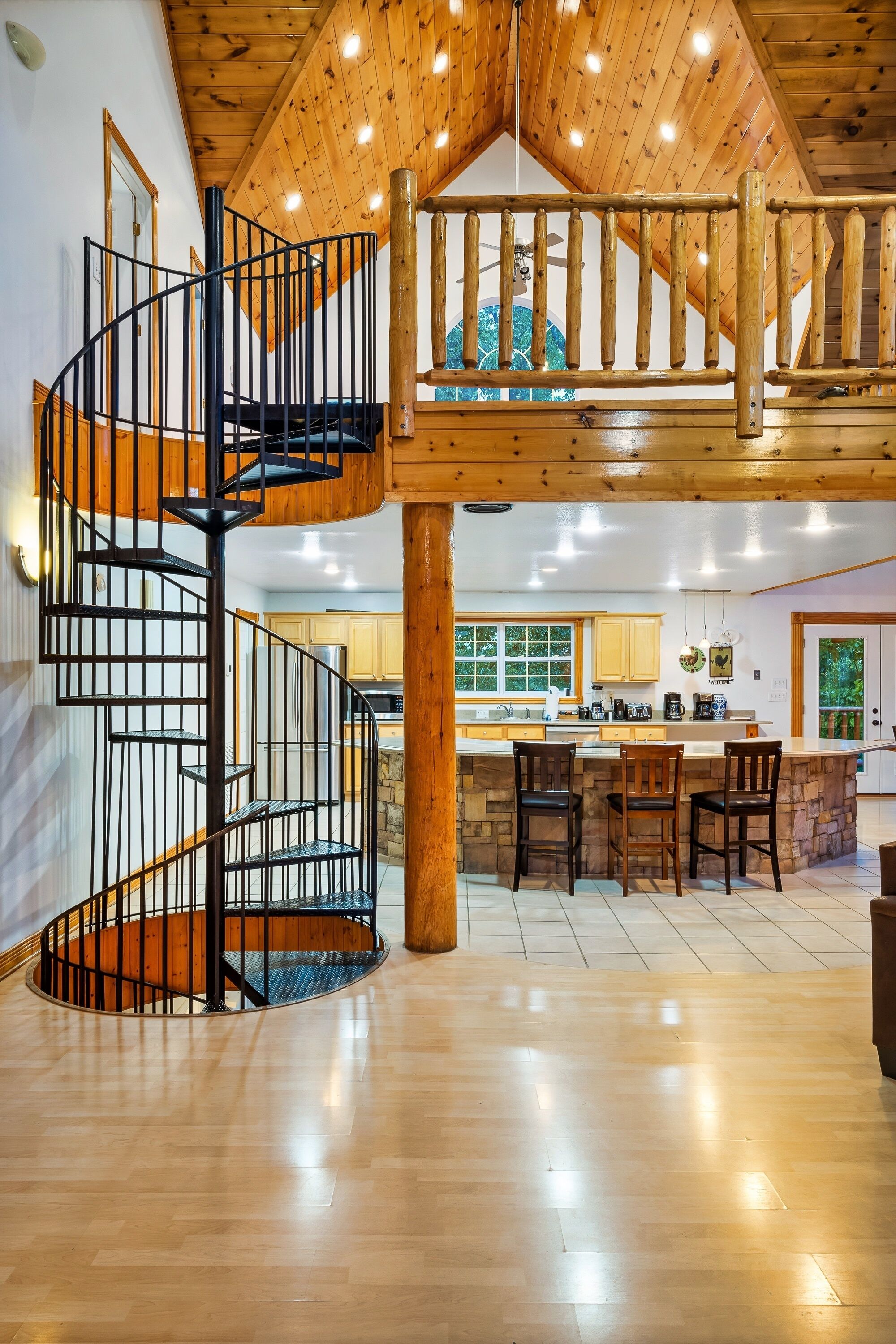 A spacious interior with a wooden staircase, a kitchen area, and a dining space.