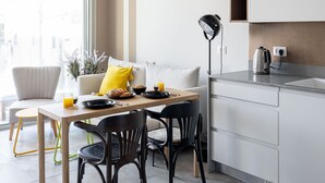 A modern kitchen with a dining area, featuring a table with chairs, a coffee machine, and a kettle. - HighQuality TelAviv Apartment in theCity (Tel Aviv)