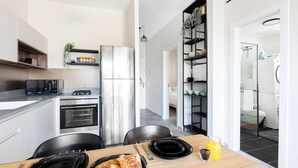 A modern kitchen with a dining area, featuring stainless steel appliances, black chairs, and a wooden table. - HighQuality TelAviv Apartment in theCity (Tel Aviv)