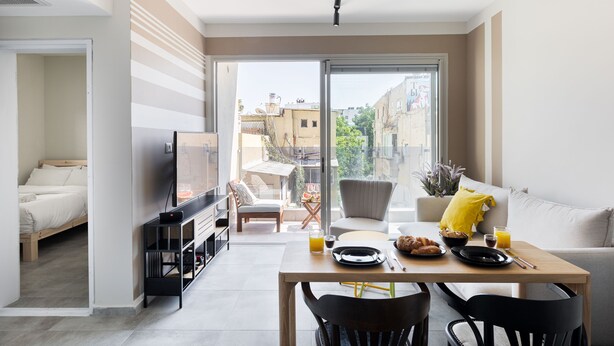 A modern living space with a dining area, a sofa, a TV, and a balcony with a city view. - HighQuality TelAviv Apartment in theCity (Tel Aviv)
