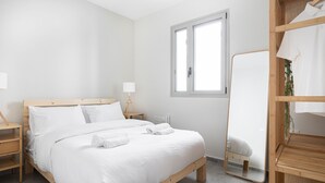 A neatly made bed with white linens, a bedside table with a lamp, a wooden nightstand, and a large mirror on the wall. - HighQuality TelAviv Apartment in theCity (Tel Aviv)
