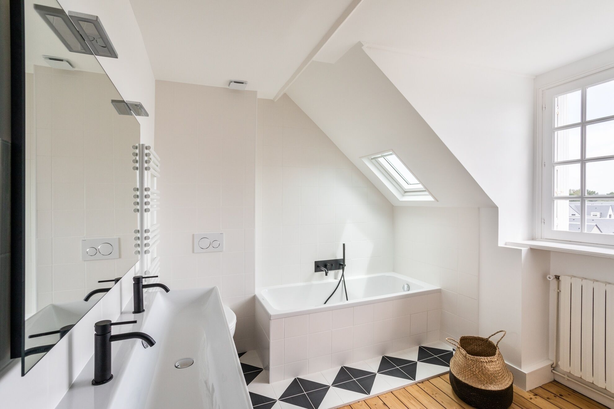 Ein modernes Badezimmer mit einem weißen Waschbecken, einer Badewanne und einem Oberlicht.