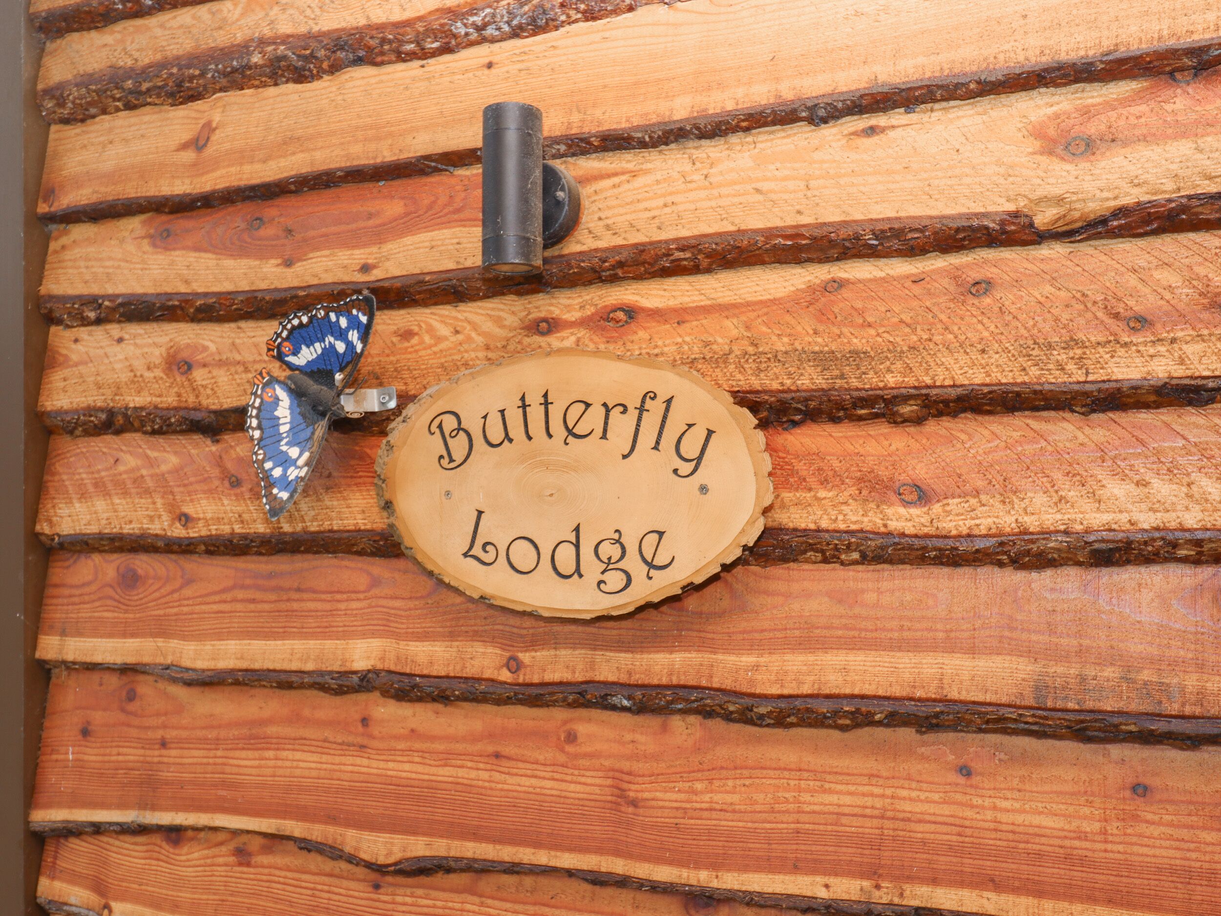 A wooden wall with a sign that reads "Butterfly Lodge."