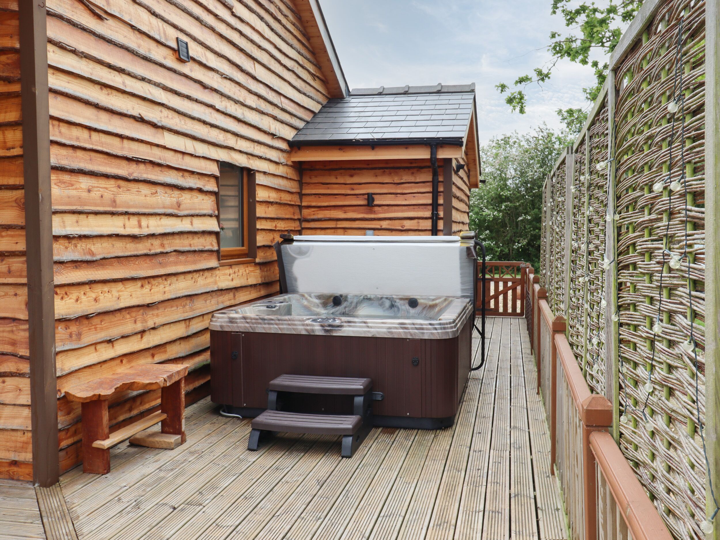 A wooden cabin with a hot tub on a deck.
