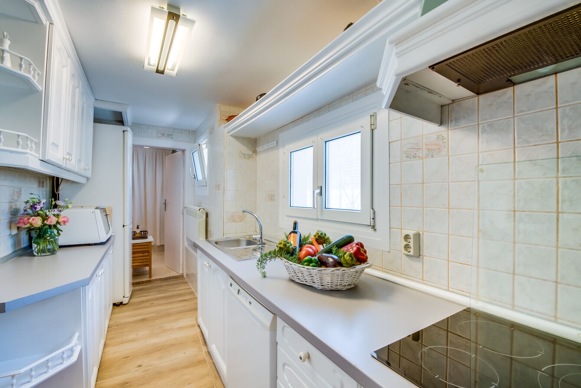 A modern kitchen with white cabinetry, a built-in oven, and a window above the sink.