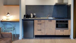 A compact kitchen with a dishwasher, oven, and a coffee maker on the counter. - Studio N#2 (Narbonne)