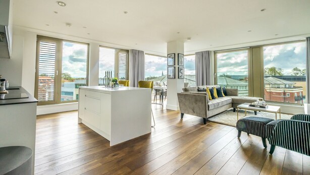 Un salón amplio con una isla de cocina, ventanas grandes y vistas a la ciudad.