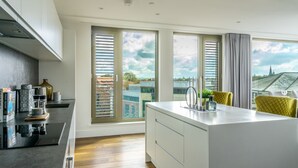 Una cocina moderna con una isla central, ventanas amplias con persianas y vistas a la ciudad.
