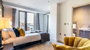 Una habitación de hotel moderna con una cama grande, un sillón amarillo y vistas a la ciudad desde la ventana.