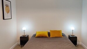 Ein Schlafzimmer mit einem Bett, zwei Nachttischen und einem gerahmten Bild an der Wand.