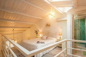 A bedroom with a bed, bedside lamps, a nightstand, a window, and a balcony railing. - Alghero Old Town. Chic Mediterranean Loft near the Sea. Sardinia (Alghero)