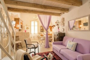 A cozy interior with a wooden ceiling, a purple sofa, a dining area, and a staircase. - Alghero Old Town. Chic Mediterranean Loft near the Sea. Sardinia (Alghero)