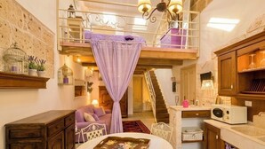 Een meerlaags interieur met een trap, een eethoek met tafel en stoelen, en een keuken met een magnetron.