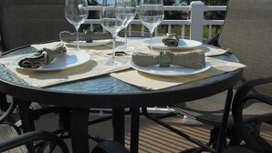 A round table with a glass top, set with plates, folded napkins, and wine glasses.