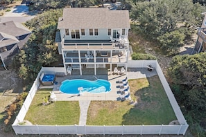 A two-story house with a swimming pool, a deck, and a fenced yard.
