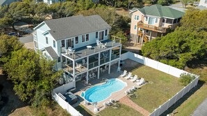 Ein zweistöckiges Haus mit Swimmingpool, überdachter Terrasse und umzäunter Garten.