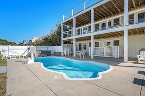 A two-story house with a swimming pool, outdoor furniture, and a covered patio area.