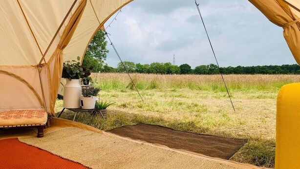 A tent with a bed and a view of a field. - Private Glamping in a Vintage Caravan & Bell Tent (Morpeth)