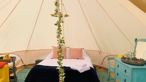 A tent with a bed, a dresser, and a hanging plant. - Private Glamping in a Vintage Caravan & Bell Tent (Morpeth)