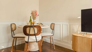 Een eetruimte met een ronde tafel, vier stoelen en een bijzettafeltje met een televisie.