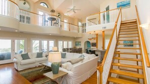 A spacious living area with a high ceiling, a wooden staircase, and a balcony with a view. - Luxury Oceanside Pool Home Boasting Incredible Views - Large 5/3 w/Heated Pool (St. Augustine)
