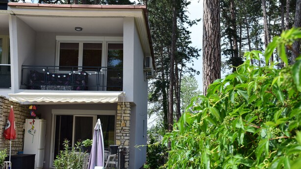 Un edificio a due piani con un balcone, una facciata in pietra e un vialetto sterrato che conduce all'ingresso.
