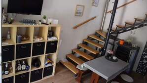 Un soggiorno moderno con televisione, una scala in legno e un'accogliente area salotto.