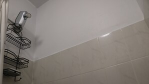 A bathroom with a shower, tiled walls, and a hairdryer mounted on the wall. - The Charming Unit (5 minutes from Airport) (Carolina)