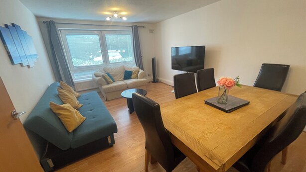 Una sala de estar moderna con un sofá, una mesa de comedor y un televisor.