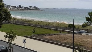 Una carretera costera con una mediana verde, una playa y vistas al mar.