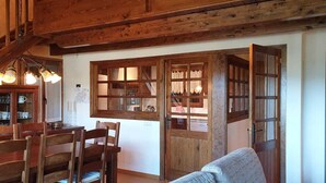 A wooden dining area with a table and chairs, a staircase, and a window with curtains.
