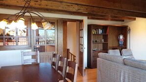 A dining area with a wooden table and chairs, a sofa, a bookshelf, and a television.