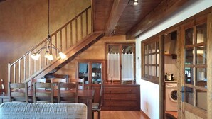 A rustic interior with a wooden staircase, dining area, and a laundry room.