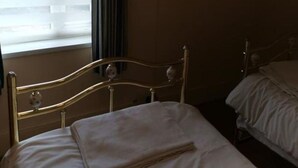 Ein Einzelbett mit Metallkopfteil und einem an der Wand befestigten Fernseher.
