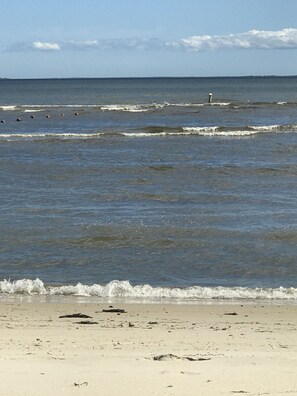 A beach with waves and a distant figure on the shore.
