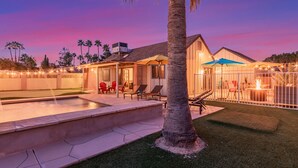 Un jardin avec une piscine, un espace salon extérieur et une terrasse couverte.