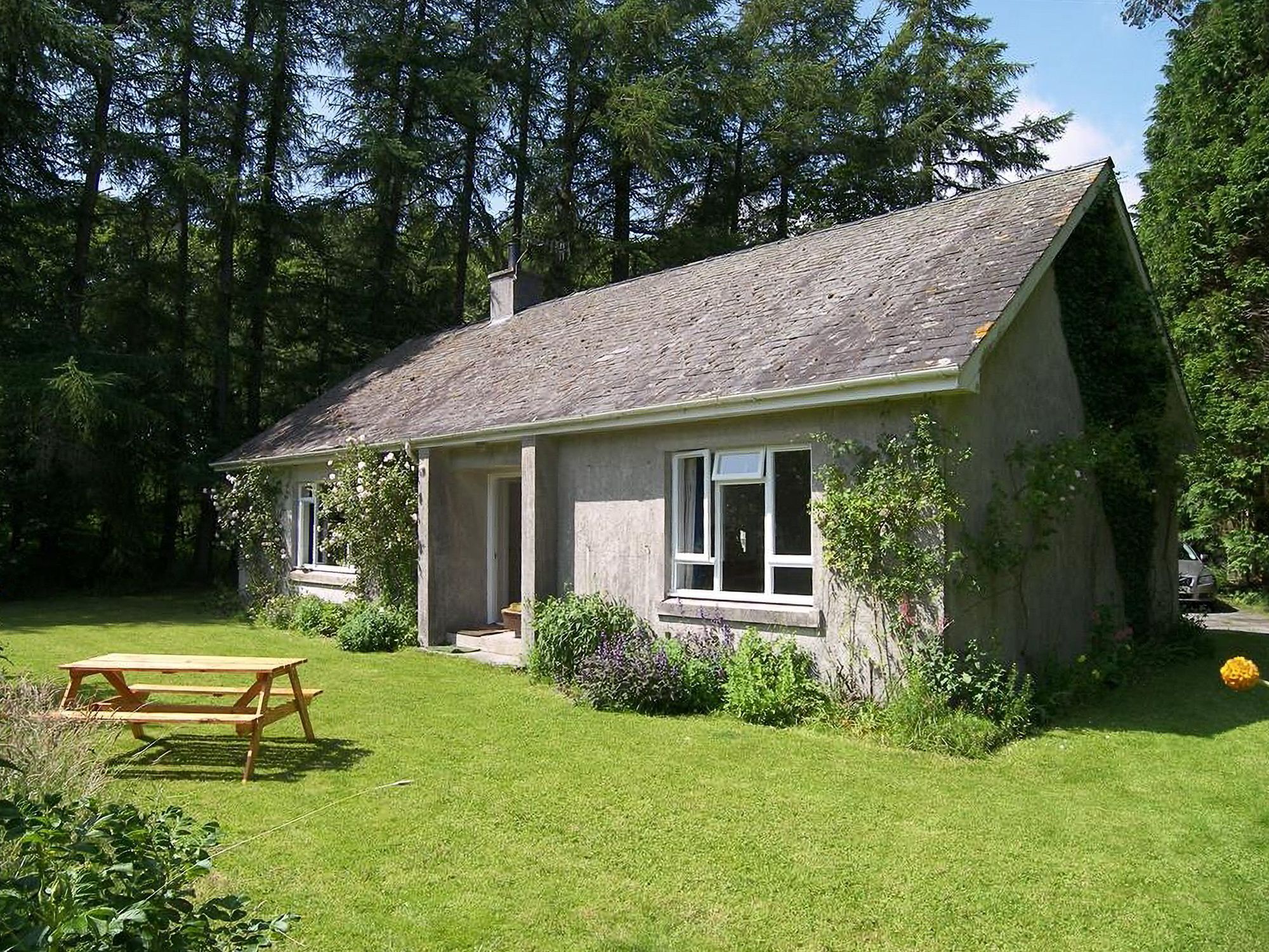 A single-story house with a sloped roof, a front porch, and a small garden area.