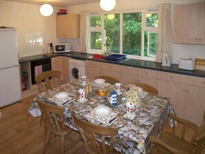 A compact kitchen with a dining table set for two, a washing machine, and a microwave.