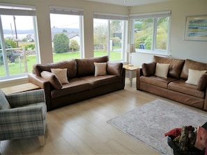A living room with two brown leather sofas, a plaid armchair, and a wooden coffee table.