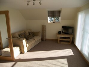 A living room with a sofa, a television, a window with curtains, and a floor lamp. - Criffel Glen - a house that sleeps 6 guests in 3 bedrooms (Kirkbean, New Abbey)