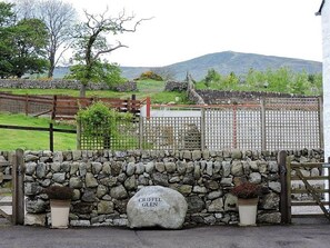 Un mur de pierres sur lequel est fixée une plaque portant l’inscription « CRIFEL GLEN », ainsi qu’une porte en bois.