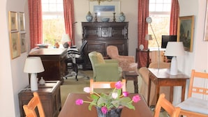 Een eetkamer met een houten tafel, stoelen, een vaas met bloemen en een open haard.