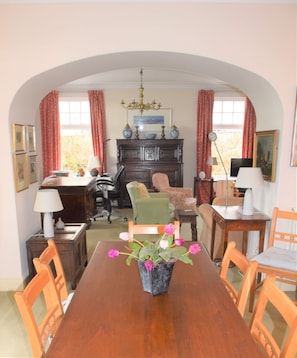 A dining room with a wooden table, chairs, a vase with flowers, and a fireplace.