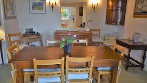 Een eetruimte met een houten tafel en stoelen, een vaas met bloemen en wandlampen.