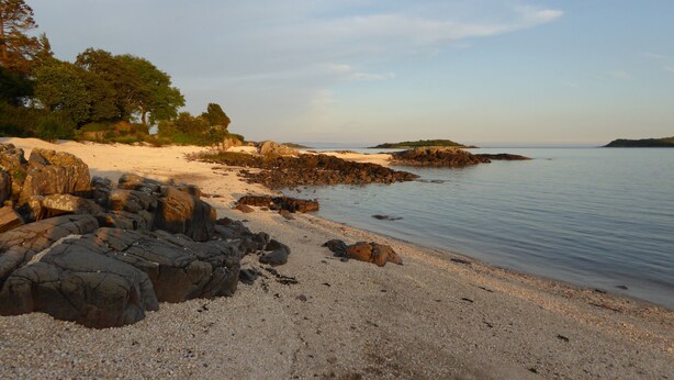 A beach with pebbly shore, large rocks, and distant islands. - Elm Cottage -  a house that sleeps 8 guests  in 4 bedrooms (Dalbeattie)